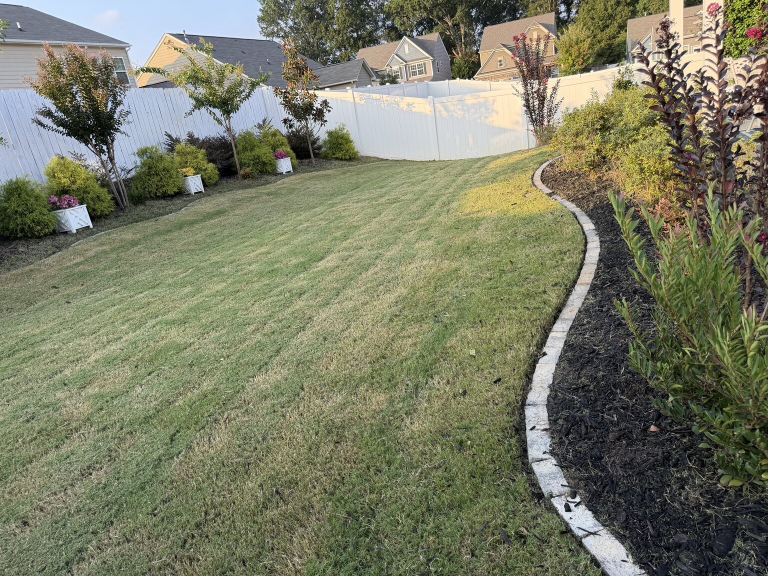 Maintained backyard lawn beside a curved freshly mulched garden bed